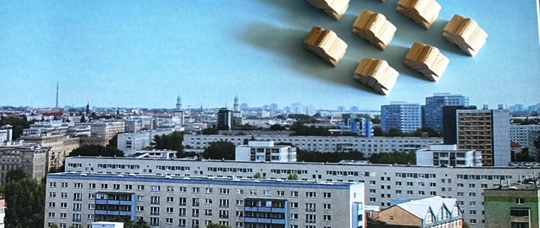 Stadtbild mit Mehrfamilienhäusern, Im Vordergrund ein Objekt der Wohnungsbaugenossenschaft Solidarität eG, darauf stehen kleine menschliche Holzfiguren