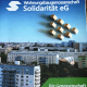 Stadtbild mit Mehrfamilienhäusern, Im Vordergrund ein Objekt der Wohnungsbaugenossenschaft Solidarität eG, darauf stehen kleine menschliche Holzfiguren