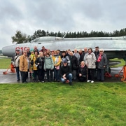 eine Gruppe von Männern und Frauen stehen vor einem alten Flugzeug