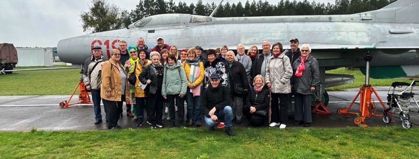 eine Gruppe von Männern und Frauen stehen vor einem alten Flugzeug