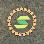 ein gr&uuml;nes S von unserem Logo umrandet von kleinen Menschen aus Holz die im Kreis zusammenstehen