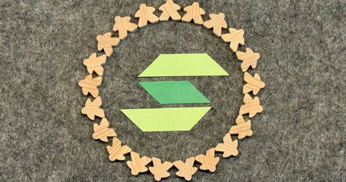WG Solidarität ein grünes S von unserem Logo umrandet von kleinen Menschen aus Holz die im Kreis zusammenstehen
