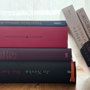 Stapel von vier B&uuml;chern, zwei B&uuml;cher lehnen seitlich am Stapel