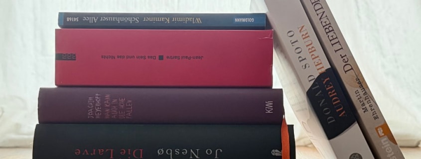 Stapel von vier B&uuml;chern, zwei B&uuml;cher lehnen seitlich am Stapel