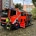 Ein Feuerwehreinsatzwagen steht mit ge&ouml;ffneten T&uuml;ren und sichtbarer Einsatzkleidung vor einem Wohnhaus