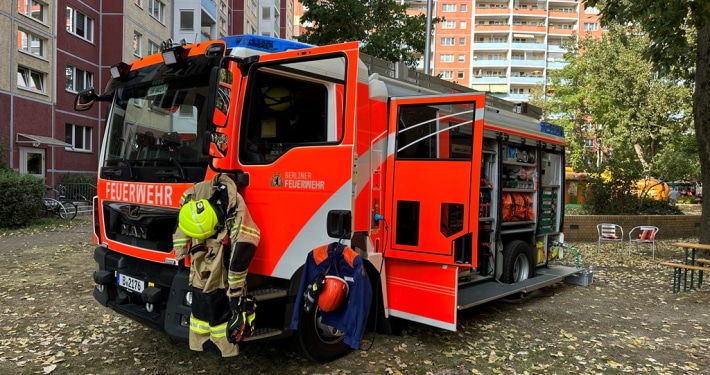 WG Solidarität Ein Feuerwehreinsatzwagen steht mit geöffneten Türen und sichtbarer Einsatzkleidung vor einem Wohnhaus