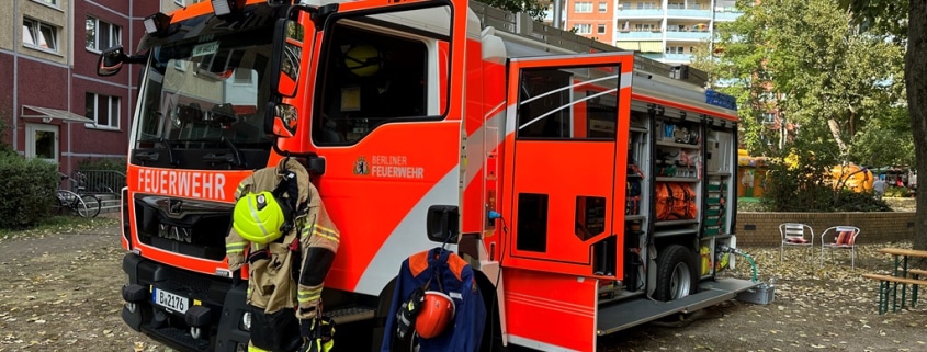 Ein Feuerwehreinsatzwagen steht mit geöffneten Türen und sichtbarer Einsatzkleidung vor einem Wohnhaus