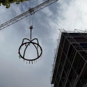Richtkranz wird mittels eines Krahns auf den Neubau eines Mehrfamilienhauses gehoben