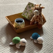 Tablett mit einer Tasse Tee dekoriert mit einer kleinen Kuscheltiergiraffe. Davor liegen zwei kleine geh&auml;kelten Schildkr&ouml;ten.